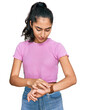 © Krakenimages.com - Hispanic teenager girl with dental braces wearing casual clothes checking the time on wrist watch, relaxed and confident