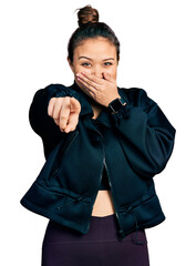 Sticker - Young hispanic girl wearing sportswear laughing at you, pointing finger to the camera with hand over mouth, shame expression