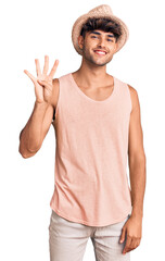 Wall Mural - Young hispanic man wearing summer hat showing and pointing up with fingers number four while smiling confident and happy.