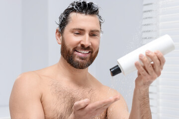 Poster - Happy man pouring shampoo onto his hand in shower