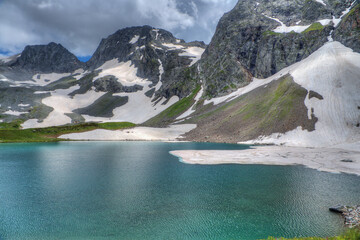 Wall Mural - The lake is surrounded by high mountains with snowfields.