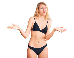 Wall Mural - Young beautiful blonde woman wearing bikini clueless and confused with open arms, no idea concept.