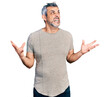 Middle age hispanic with grey hair wearing casual grey t shirt crazy and mad shouting and yelling with aggressive expression and arms raised. frustration concept.