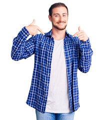 Wall Mural - Young handsome caucasian man wearing casual clothes looking confident with smile on face, pointing oneself with fingers proud and happy.