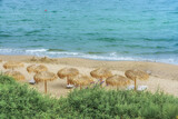 Fototapeta Boho - Holidays on the seaside. The beach straw parasols and lounge chairs on sandy beach. Calm and tranquility.