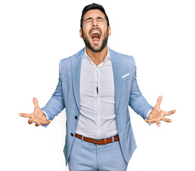 Wall Mural - Young hispanic man wearing business jacket crazy and mad shouting and yelling with aggressive expression and arms raised. frustration concept.