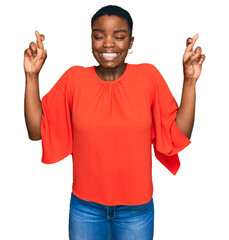 Poster - Young african american woman wearing casual clothes gesturing finger crossed smiling with hope and eyes closed. luck and superstitious concept.