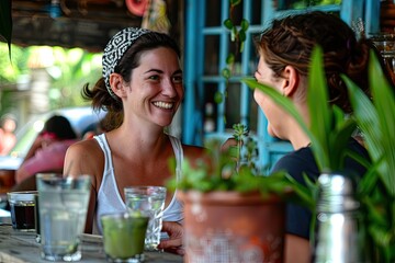 Wall Mural - Two women are sitting at a table in a restaurant, smiling and talking