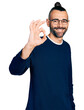 Hispanic man with ponytail wearing casual sweater and glasses smiling positive doing ok sign with hand and fingers. successful expression.