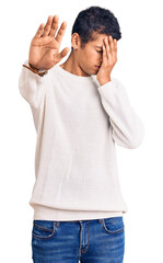 Sticker - Young african amercian man wearing casual clothes covering eyes with hands and doing stop gesture with sad and fear expression. embarrassed and negative concept.