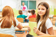 © Robert Kneschke - Girl holding book while sitting in class