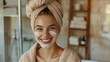 Smiling woman with a towel turban and facial cream.