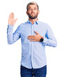 © Krakenimages.com - Young handsome blond man wearing elegant shirt swearing with hand on chest and open palm, making a loyalty promise oath