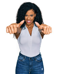 Wall Mural - Middle age african american woman wearing casual style with sleeveless shirt approving doing positive gesture with hand, thumbs up smiling and happy for success. winner gesture.