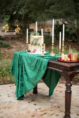 Wall Mural - Outdoor dining setup with a green tablecloth, tall candles, and a ceremony cake