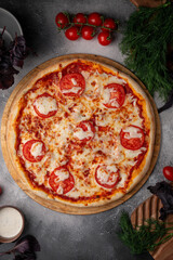 Wall Mural - Tomato and cheese pizza with spiced tomatoes and cheese on a grey table