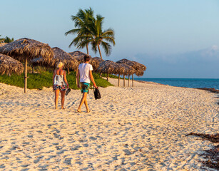 Wall Mural - Shot of the young couple walking by the beach at the sunrise hour. Holiday