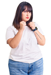 Sticker - Young plus size woman wearing casual clothes ready to fight with fist defense gesture, angry and upset face, afraid of problem