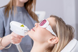 Fototapeta Psy - Professional beautician removes hair on the face of an young woman using a laser. Mustache and beard removal, laser procedure at clinic