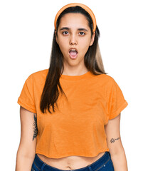 Wall Mural - Young hispanic woman wearing casual clothes in shock face, looking skeptical and sarcastic, surprised with open mouth