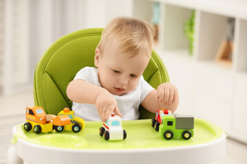 Sticker - Children toys. Cute little boy playing with toy cars in high chair at home