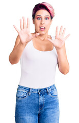 Poster - Young beautiful woman with pink hair wearing casual clothes afraid and terrified with fear expression stop gesture with hands, shouting in shock. panic concept.