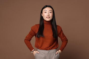 Wall Mural - Portrait of smiling woman on brown background