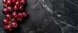  A group of cherries resting on a dark countertop beside a marble slab countertop