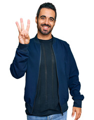 Wall Mural - Young hispanic man wearing casual clothes showing and pointing up with fingers number three while smiling confident and happy.