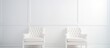 Two white chairs are placed next to each other in a room with a white wall. The chairs are simple in design and create a minimalistic look in the room.
