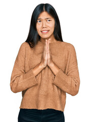 Poster - Beautiful young asian woman wearing casual winter sweater begging and praying with hands together with hope expression on face very emotional and worried. begging.