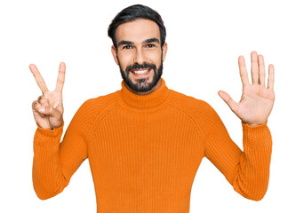 Wall Mural - Young hispanic man wearing casual clothes showing and pointing up with fingers number seven while smiling confident and happy.