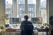 © MariiaDemchenko - Man working on computer in cozy home office with natural light. Back view. Remote work from home, telecommuting, freelance