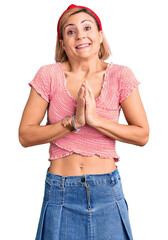 Poster - Young blonde woman wearing casual clothes and diadem praying with hands together asking for forgiveness smiling confident.