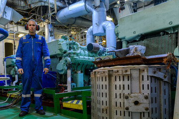 Wall Mural - Marine Engineer in blue overall working in Engine room of ship. Work at sea. Motorman.