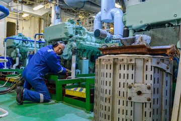 Wall Mural - Marine Engineer in blue overall working in Engine room of ship. Work at sea. Motorman.