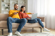 © Prostock-studio - Couple relaxing on couch with laptop and remote