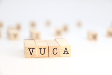 word VUCA (Volatility, Uncertainty, Complexity, Ambiguity) written on wooden cubes on a white background