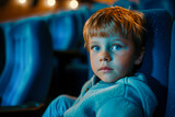 Fototapeta Zwierzęta - A young boy is sitting in a blue chair in a cinema