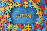 Fototapeta Mapy - Colorful puzzle pieces frame and word Autism on wooden background. World autism awareness day concept. Top view