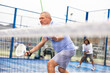 © JackF - Focused elderly European man pensioner padel player hitting ball with racket on hard court in autumn