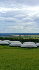 Wall Mural - Innovative biogas plant. Agriculture and greenhouse complex equipped with own biogas production. Organic farm with large storage on field. Aerial view. Vertical video