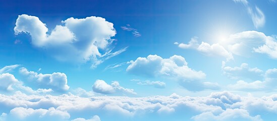 Wall Mural - Scattered white fluffy clouds float in the vast blue sky with the radiant sun shining in the center