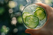  a hand holding a refreshing glass of sparkling water infused with slices of cucumber and mint, a revitalizing beverage enjoyed by city dwellers seeking respite from the summer heat