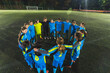 © PoppyPix - young school girls and their female coach standing in a circle and huddling before starting practice, soccer and teamwork. High quality photo