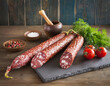Delicious coarse salami sausages on plate on decorated table