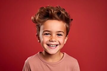 Portrait of a smiling little boy on a red background. Studio shot.