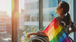 © Sophie  - Happy disabled asian female businesswoman in wheelchair celebrating gay rights parade pride month rainbow LGBTQ+ flag Diverse city woman with disability looking out inclusive office window. Copy space