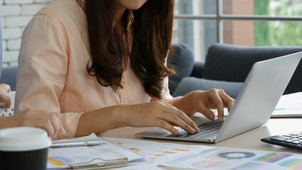 Wall Mural - Asian Female freelance using laptop at home office desk. Woman reading financial graph chart Planning analyzing marketing data. Asian female people working office firm with business stuff, coffee cup