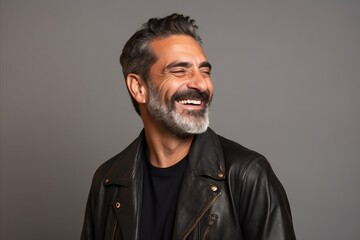 Wall Mural - Handsome middle aged man with beard and mustache in black leather jacket on grey background